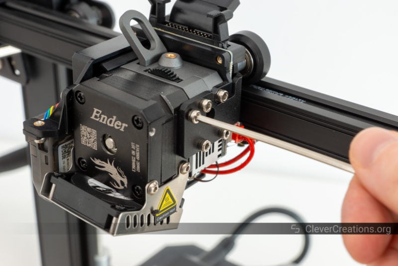 A hand using an Allen key to tighten M3 mounting bolts on a 3D printer extruder carriage