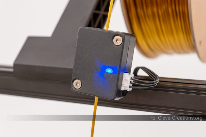 A filament runout sensor with gold filament running through it