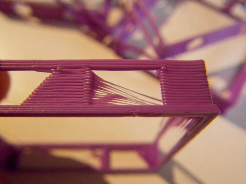 A close-up of a purple 3D print with stringing