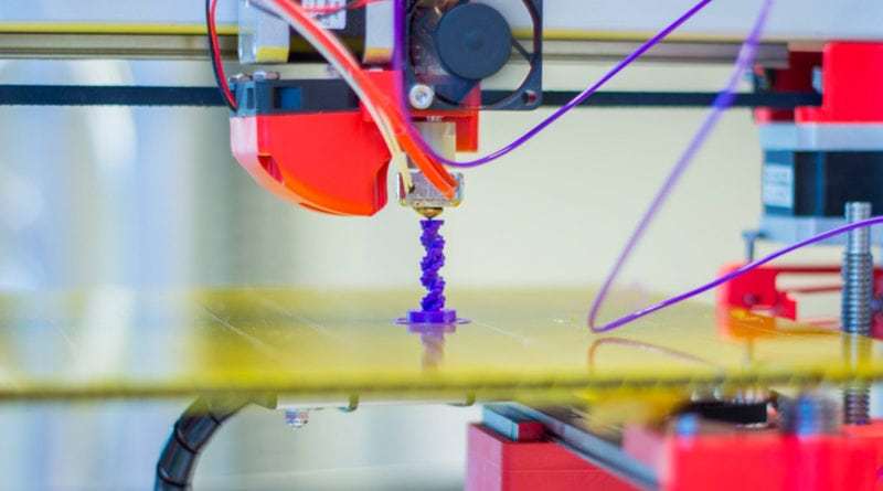 A 3D printer extruding purple filament on a build plate