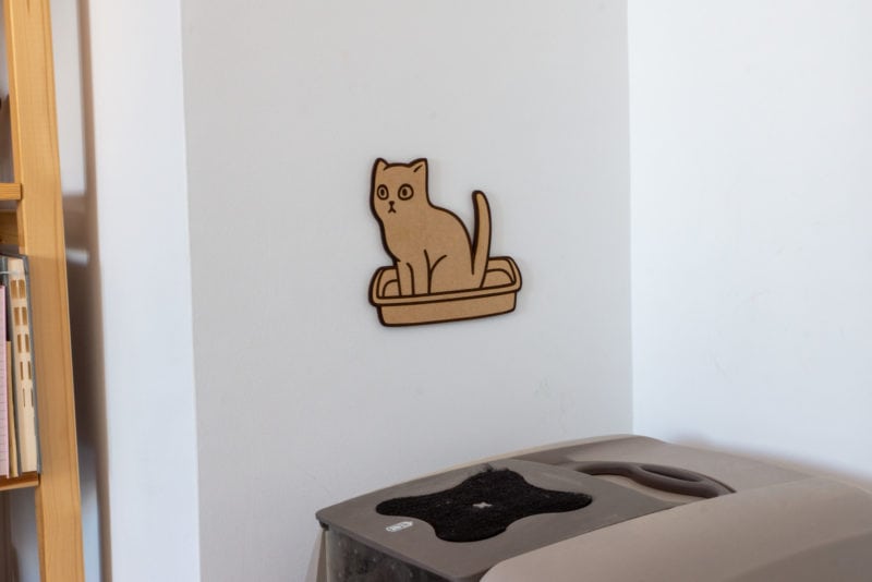 A laser cutting of a cat doing its business in a litter box