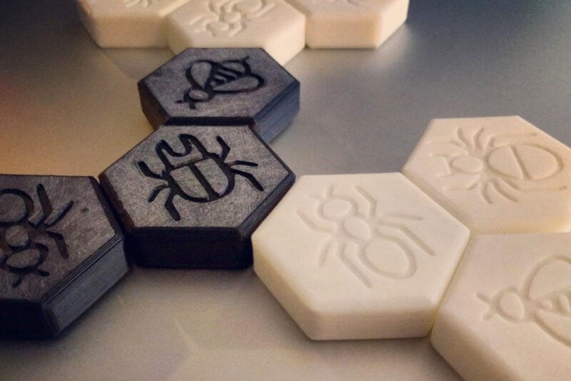 A 3D printed board game with black and white pieces based on 'Hive'