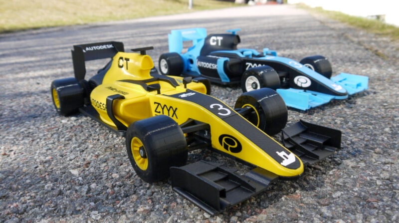 A blue and a yellow 3D printed OpenRC car on an asphalt road
