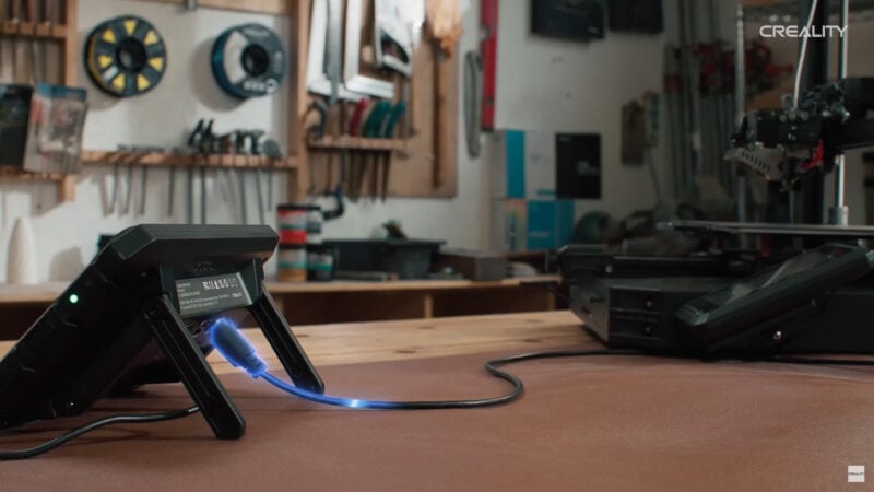 A cable coming out of an electronic device leading to a 3D printer