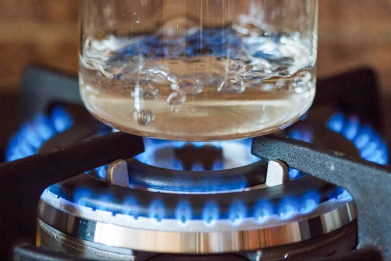 A beaker with boiling water on a stove flame