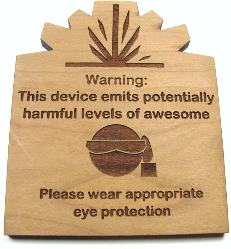 A laser cut warning sign that suggests wearing eye protection