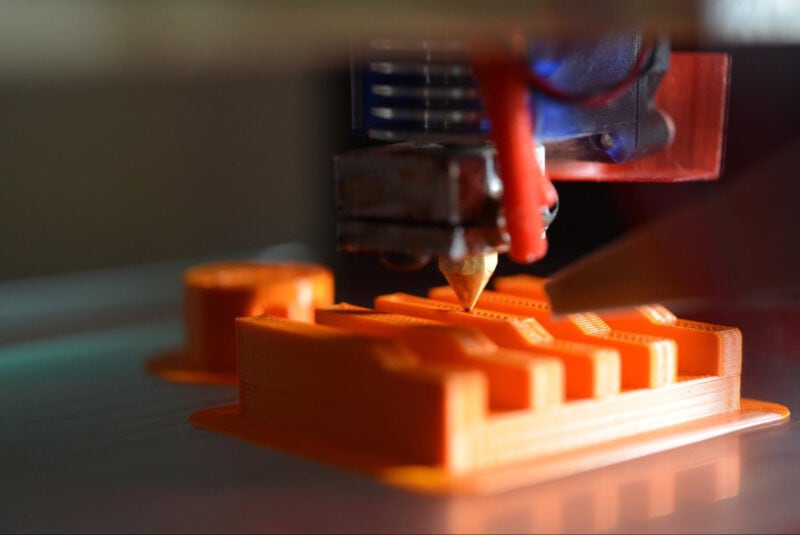 A 3D printer making an object out of orange filament