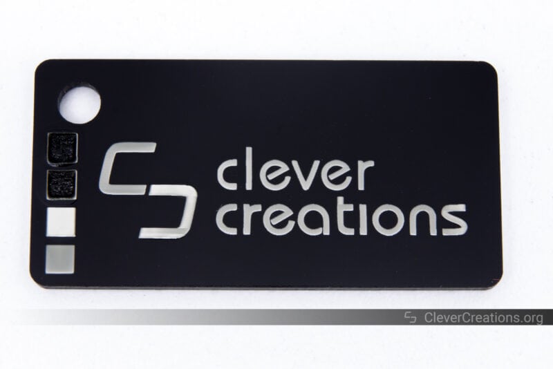 A black acrylic keychain with Clever Creations logo and text