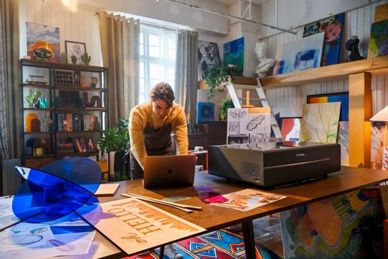 A crafting workshop with a variety of art, with a person on a laptop in the center