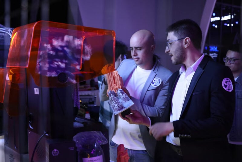Two people looking at a resin 3D print that just came out of a printer.