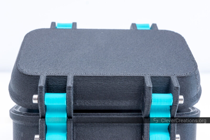 A black 3D printed rugged box with blue hinges