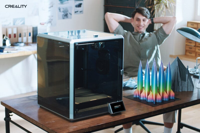 A man sitting back and watching the back of a 3D printer