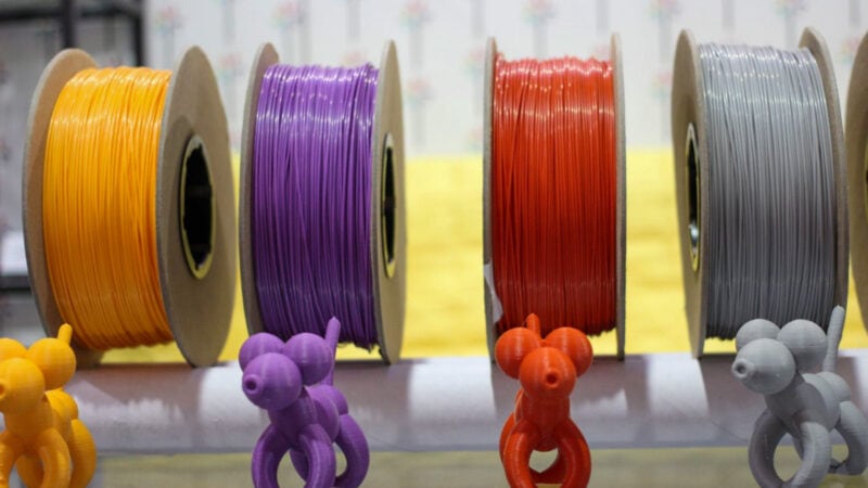 Various spools of 3D printer filament with each an example print