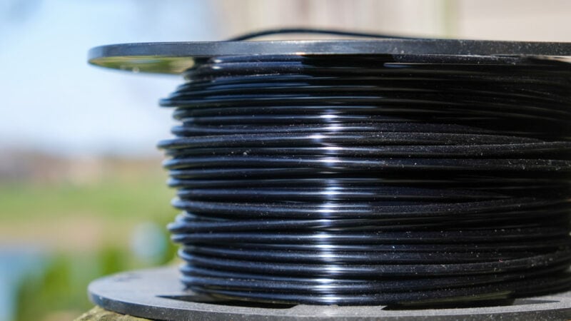 A spool of brittle PLA filament with dust on it that has been left out in the open