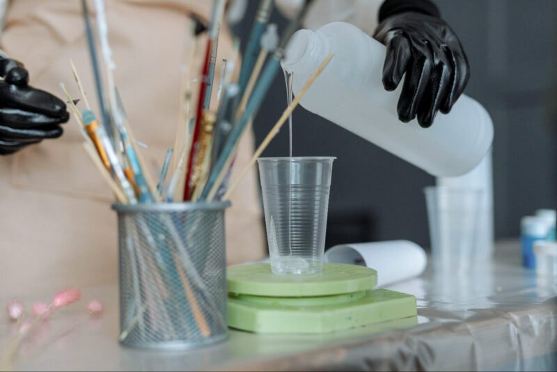 A person pouring a clear coat liquid resin in a cup