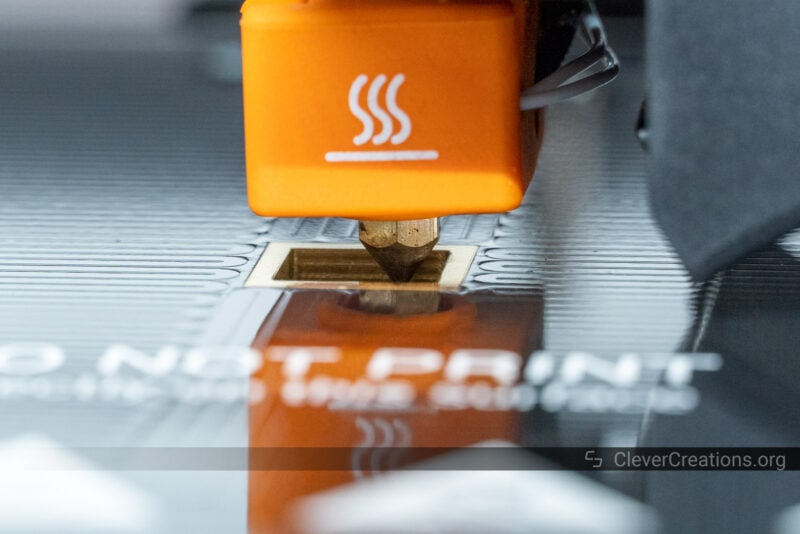 A close-up of the Snapmaker J1s hot end touching the print bed during the setup process.