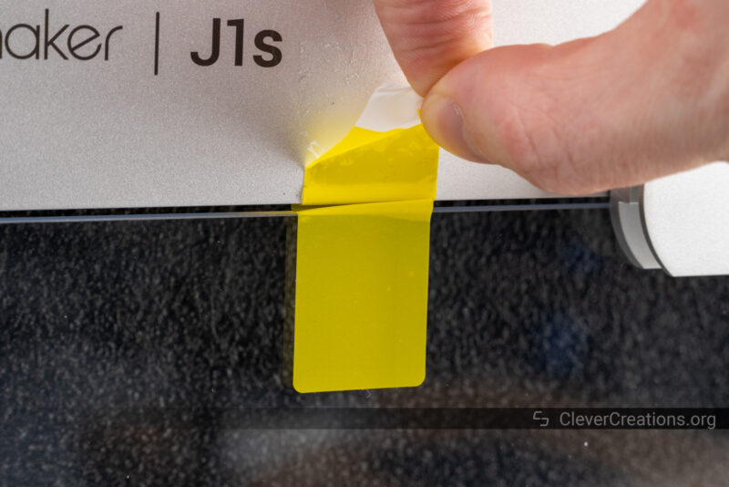 A hand peeling a yellow label off a device