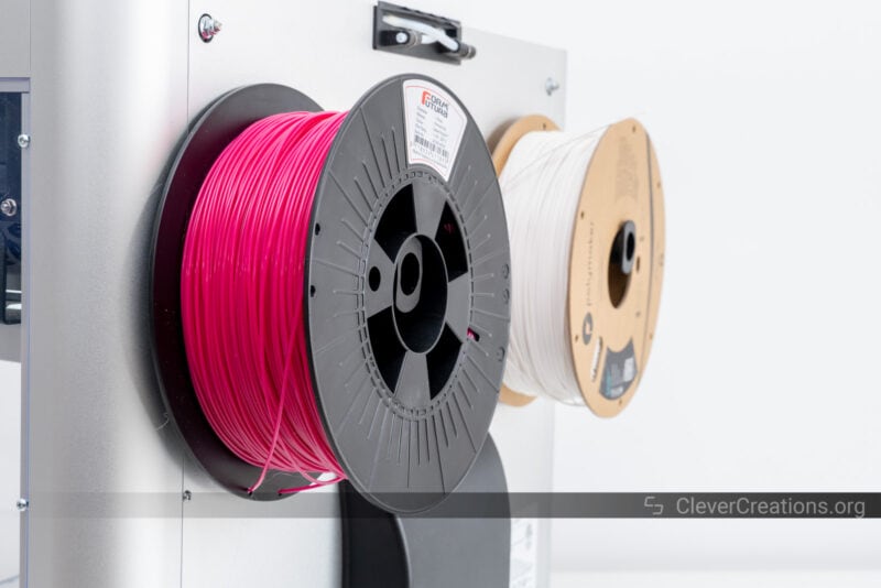 Pink and white filament rolls on dual extruder printer spool holders