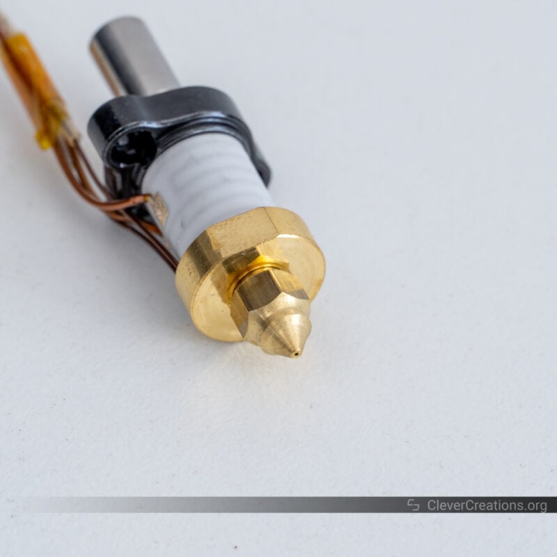 A 3D printer hot end with copper nozzle in focus