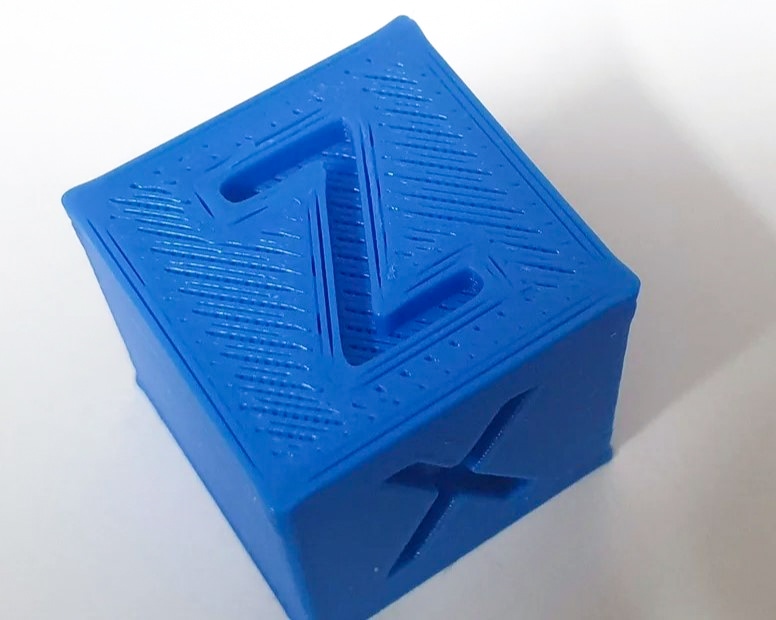 A blue 3D printed calibration cubes with gaps in the top layer