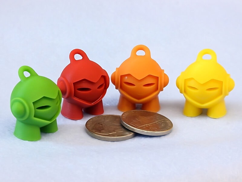 Four 3DHubs Marvin 3D prints in various colors placed around two coins