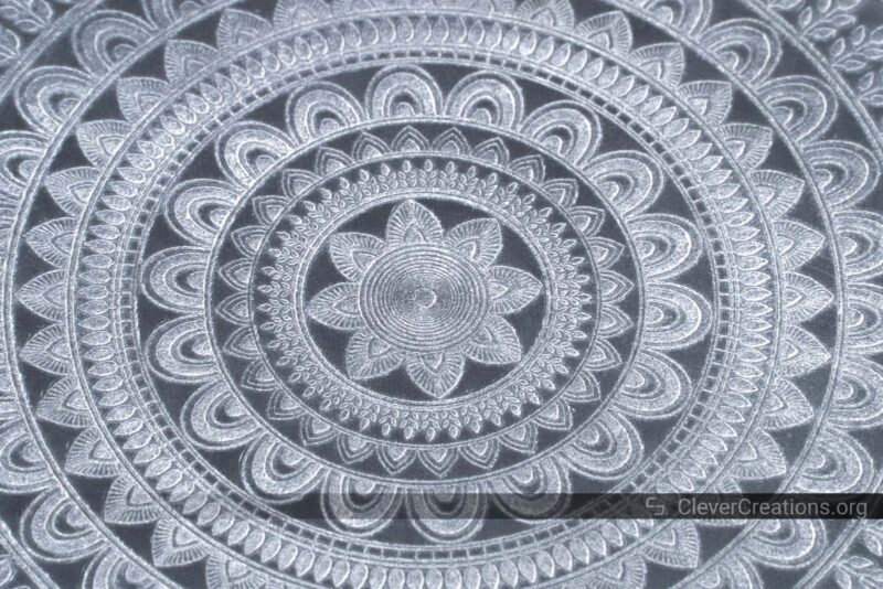 A close-up of a laser engraved clear acrylic coaster with Mandala pattern