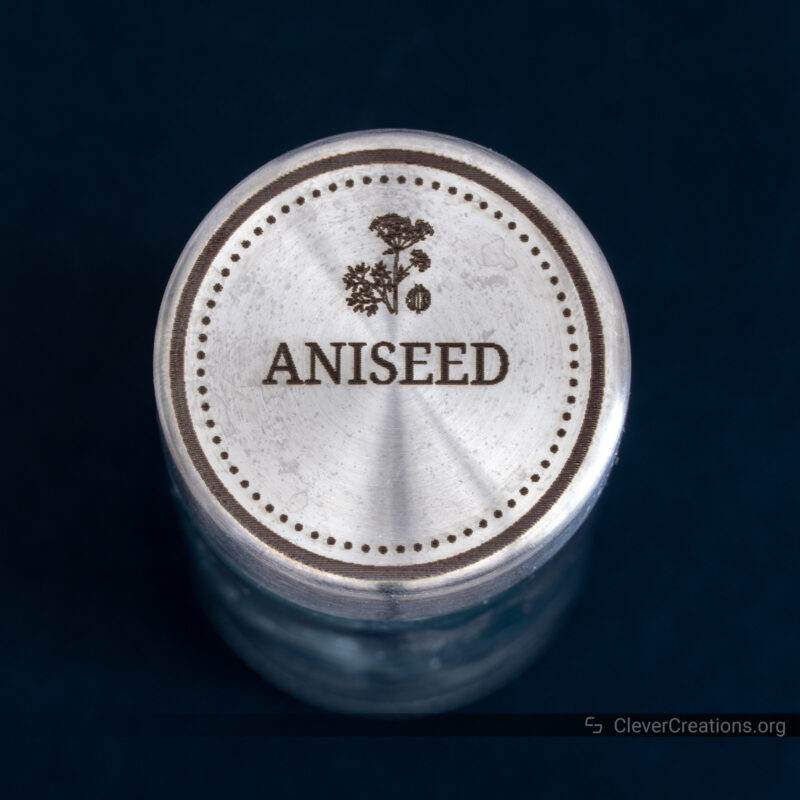 A spice jar with engraved stainless steel lid that reads 'Aniseed'