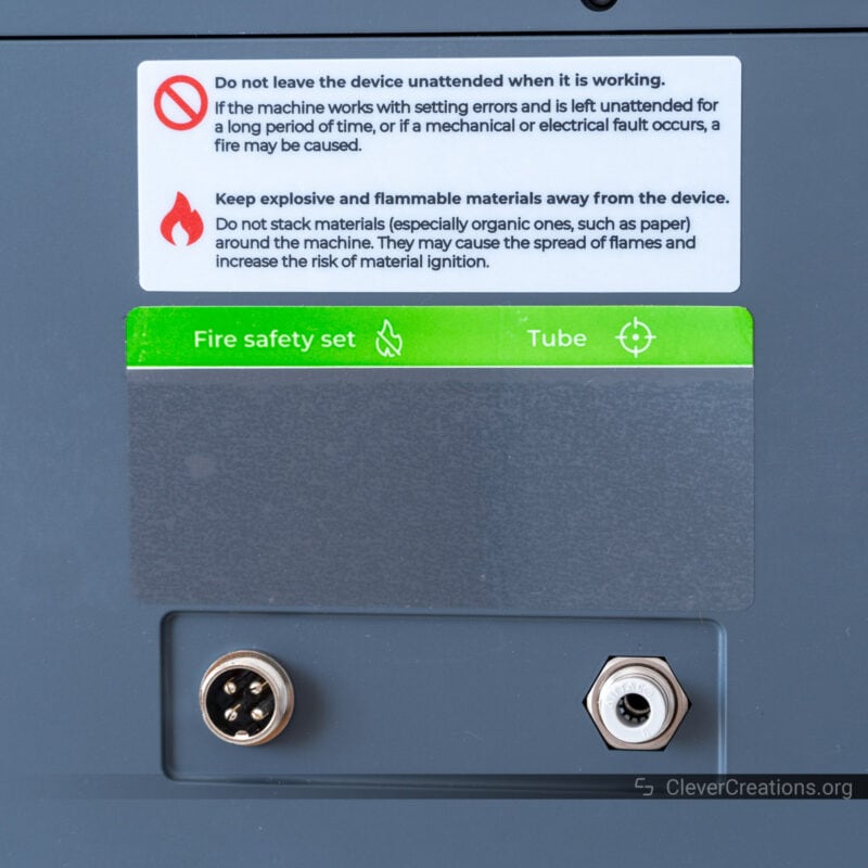 A close-up of the labels and ports of the fire safety system on a laser cutting machine