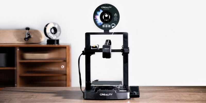 The Creality Ender-3 V3 SE 3D printer on a wooden desk in front of a cabinet.