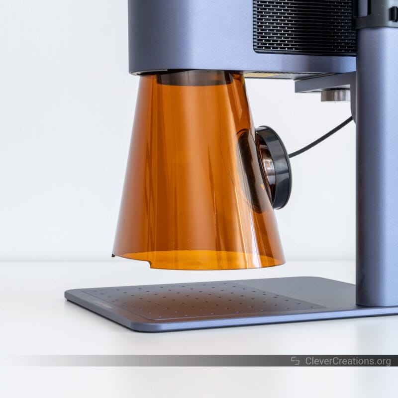 An orange light shield with integrated fan on a galvo laser engraver.