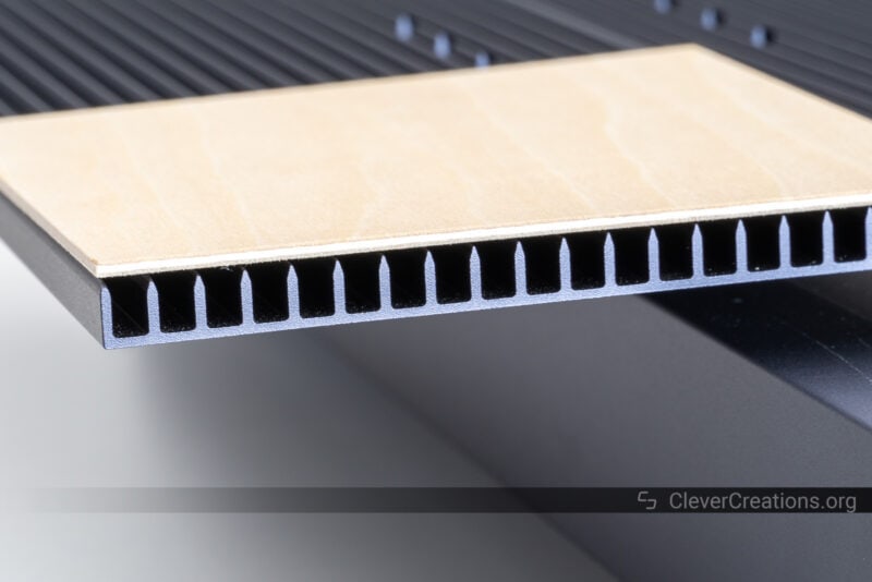 A close-up of a slatted bed for laser engraving with a piece of 1.5 mm birch plywood on top.
