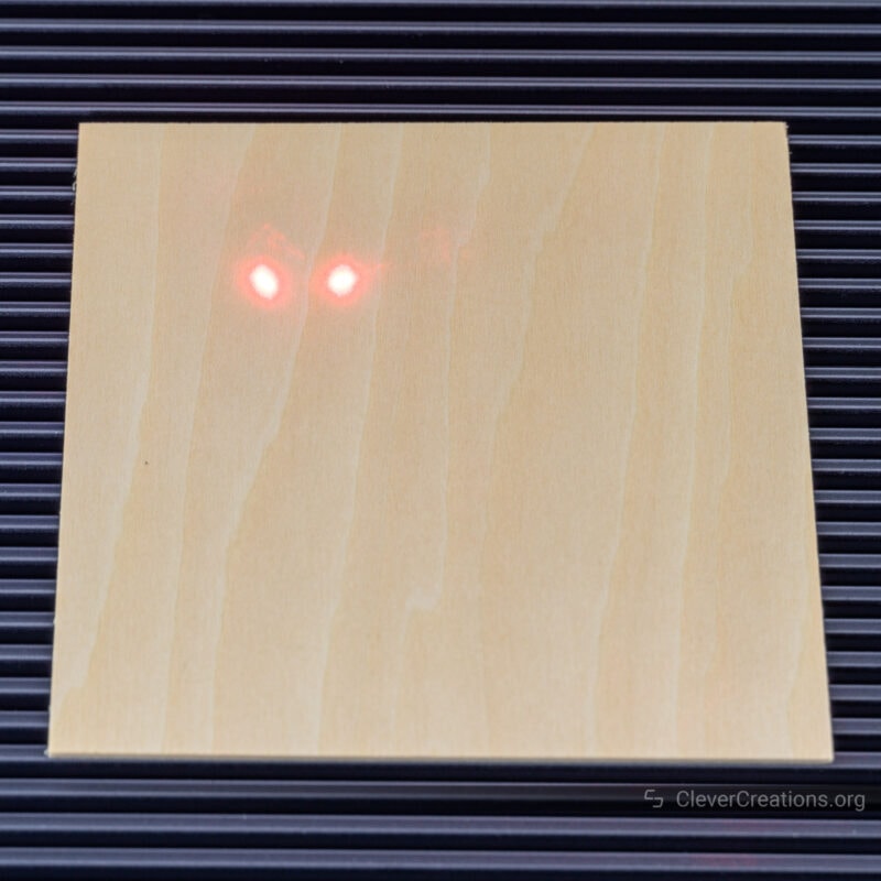 Two red laser dots separated by 10 mm on a piece of square wood, indicating that the machine is in focus.