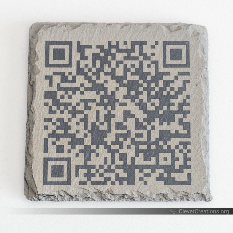 A slate stone coaster with a QR code engraved on top of it.