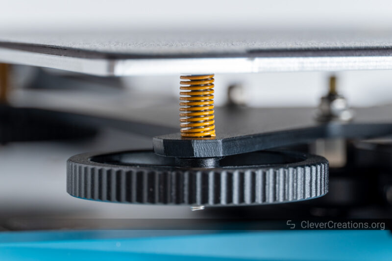 A close-up of a print bed manual bed leveling knob and spring.