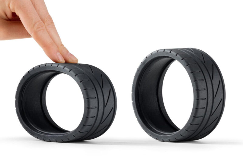 Two rubber TPU 3D printed tires, one compressed by a hand.