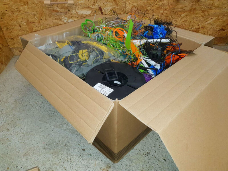 A box with various failed 3D prints and other leftover filament that needs to be disposed of.