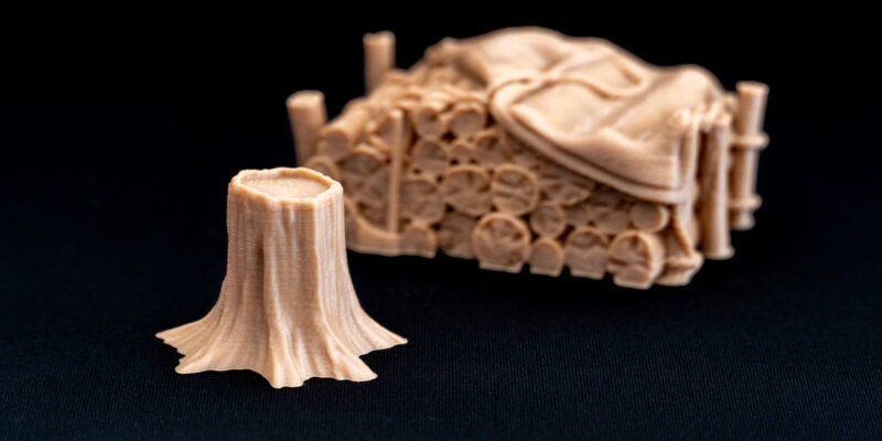 A tree and lumber stack printed with wood PLA filament on a 3D printer