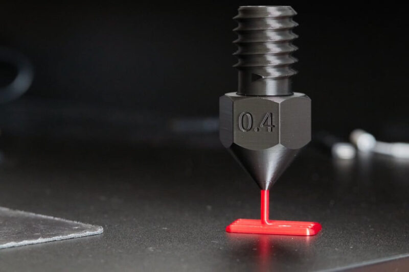 A large 3D printed nozzle with red filament.