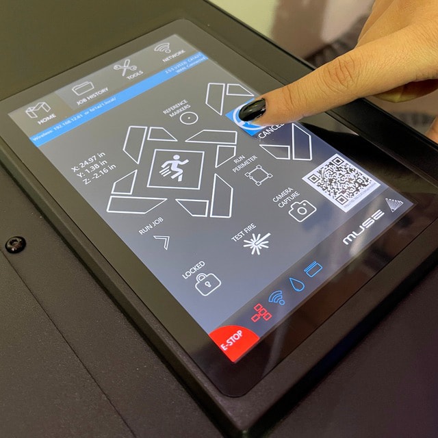 A finger pressing the touch screen of a Muse engraver