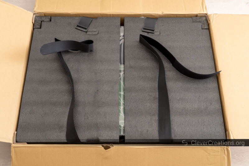 An opened box with foam padding and loosened velcro straps inside.
