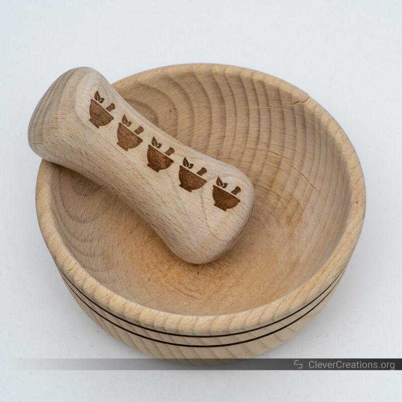 A wooden mortar and pestle set with an engraving on the pestle.
