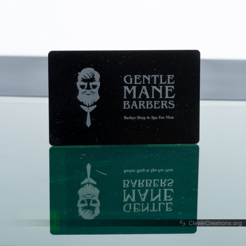 A laser engraved business card with 'Gentle Mane Barbers' text and logo.