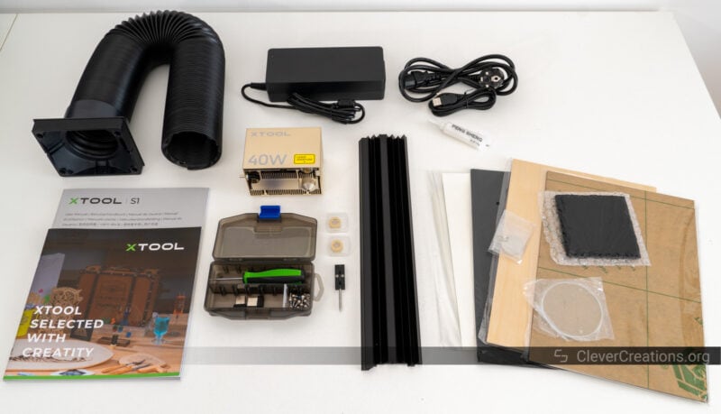 Various laser cutter parts and accessories laid out on a white table.