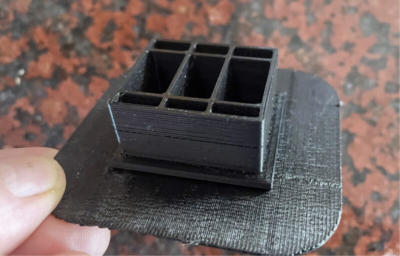 A black 3D print test with a raft to prevent ABS curling.
