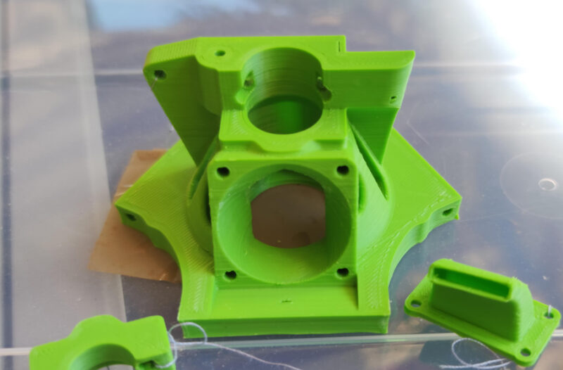 An extruder mounting bracket for a 3D printer printed in green ASA.