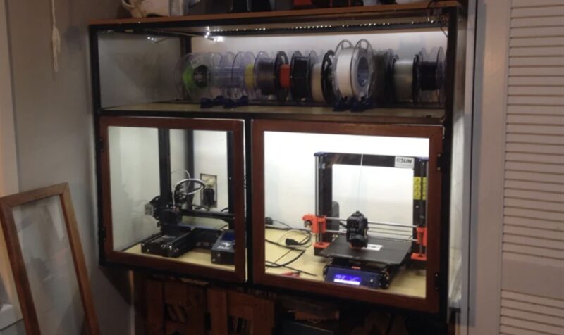 Several 3D printers in a clear enclosure used for printing ABS filament.