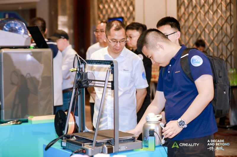 People at an event checking a 3D printer.