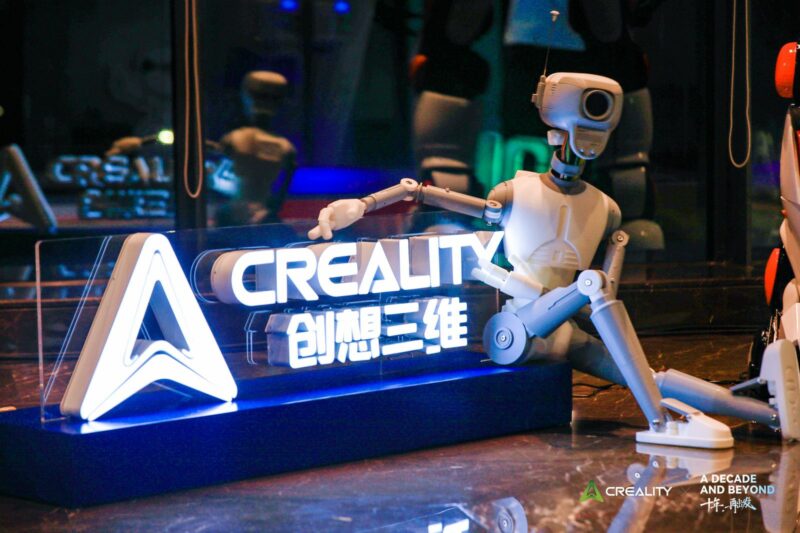 A 3D printed robot next to a neon Creality logo.