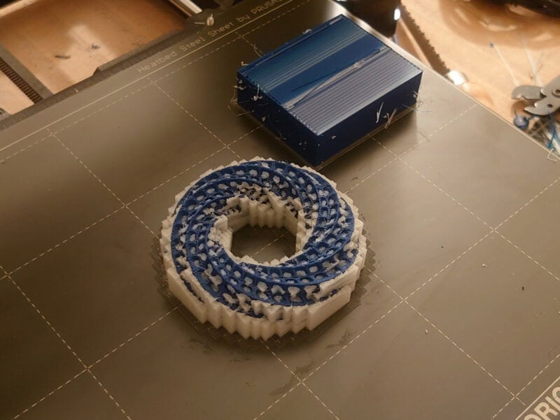 A blue helix spiral 3D print with soluble supports.