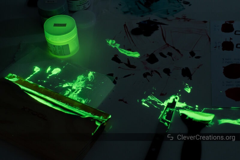 A screen printing work space with glowing paint visible in the dark.